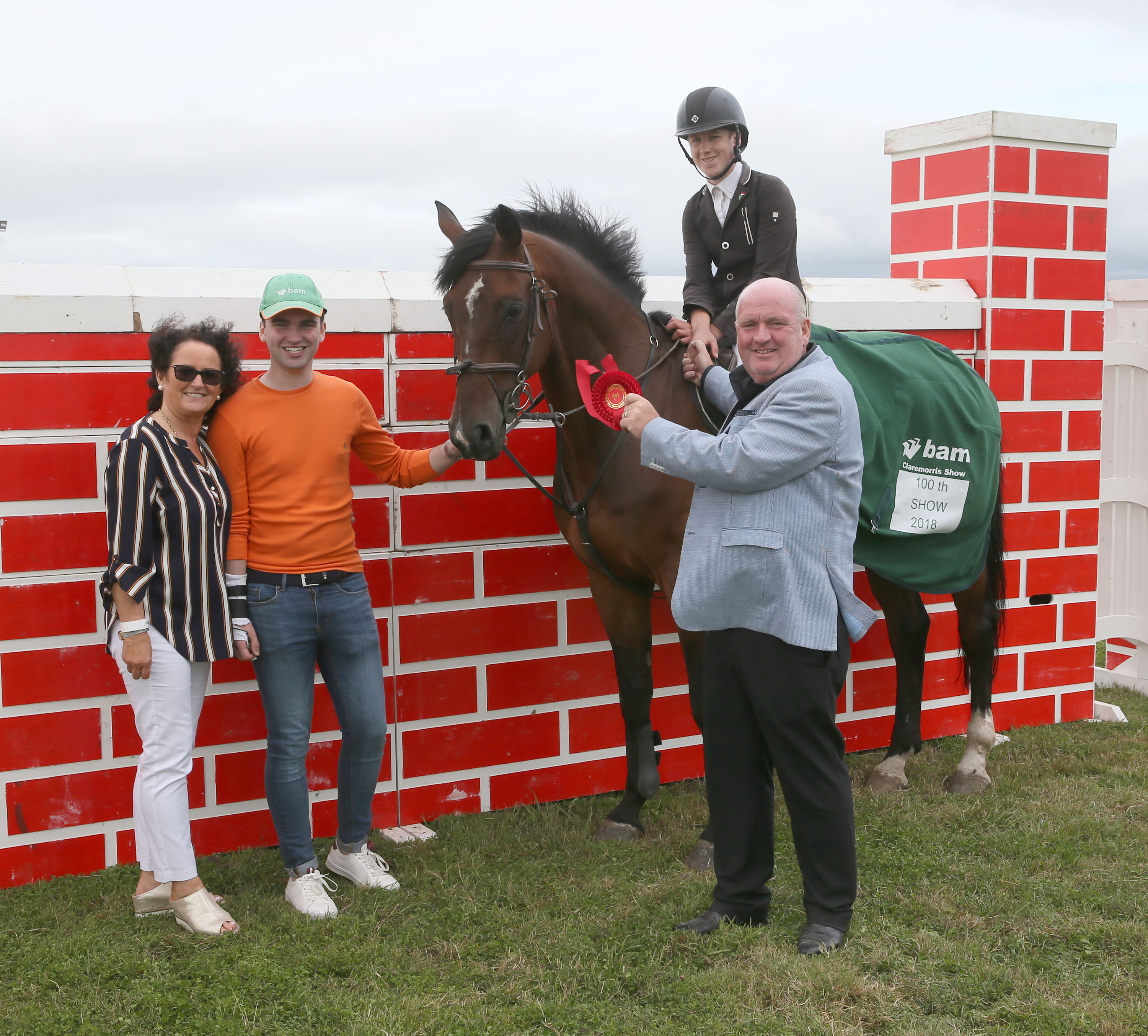 Lee Carey, Crossmolina winner of Puissance at Claremorris 100th Agricultural Show 2018 is presented with rosette by Luke Gibbons, BAM Buildings sponsor included are Francesca and Luke Gibbons, Jnr. Photo: © Michael Donnelly